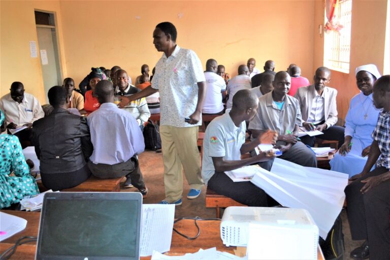 Zombo District Education Officer Training the School Management Committee Members at Zeu Community Centre in 2023